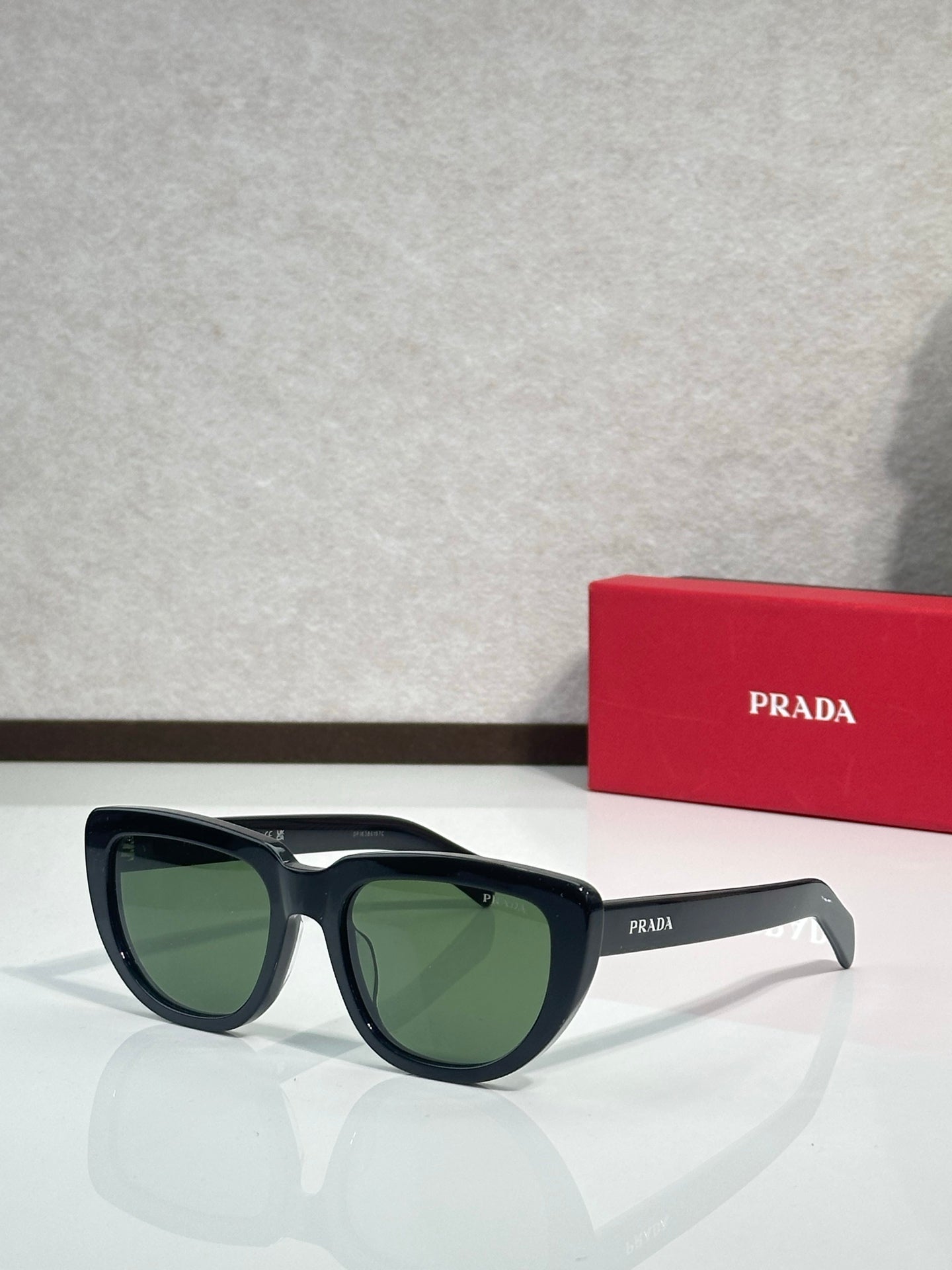 Prada sunglasses with black frames and green-tinted lenses, angled side view