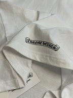 White T-shirt sleeve with Chrome Hearts logo graphic and hanging label