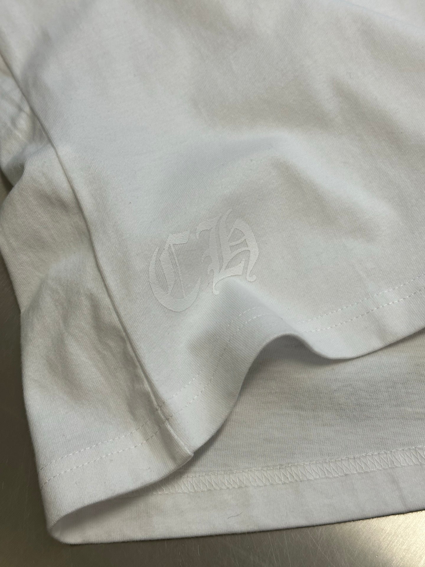 White T-shirt fabric with small embossed heart emblem near seam