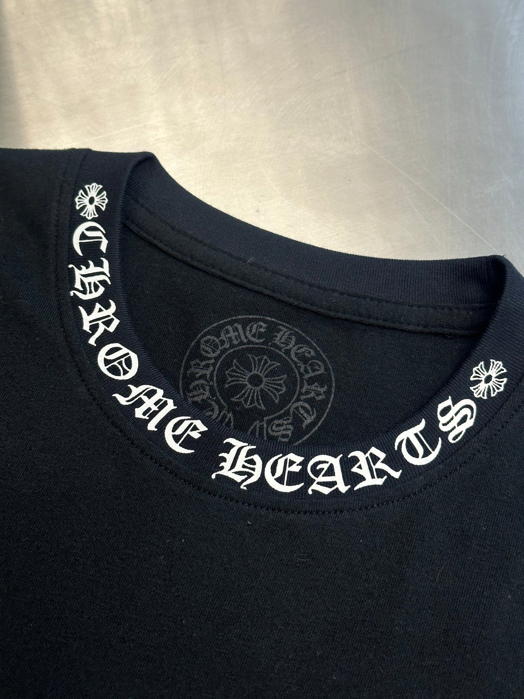 Black crewneck T-shirt with large white logo print across neckline