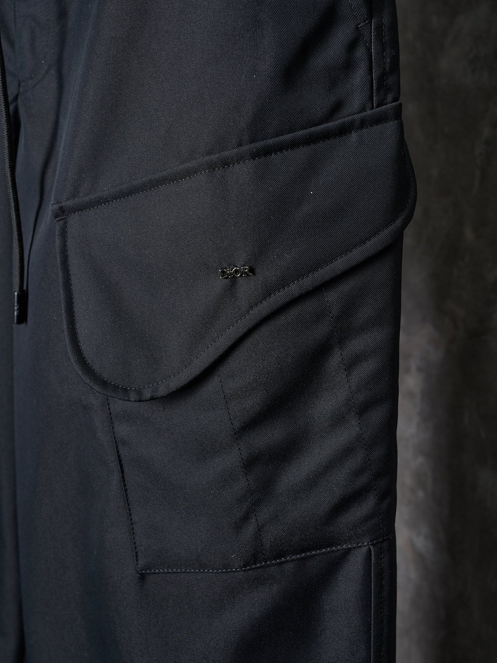 Dark pants with curved pocket flap and small embroidered logo