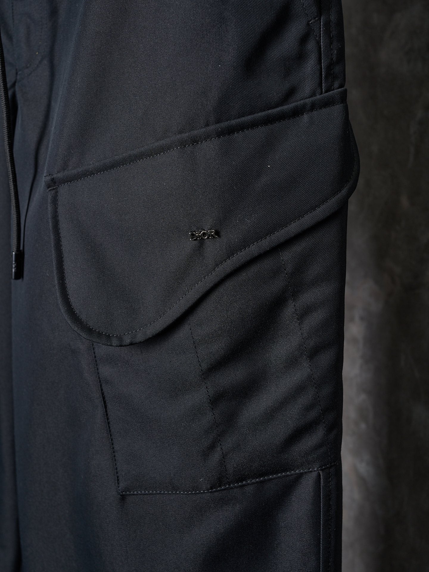 Dark pants with curved pocket flap and small embroidered logo
