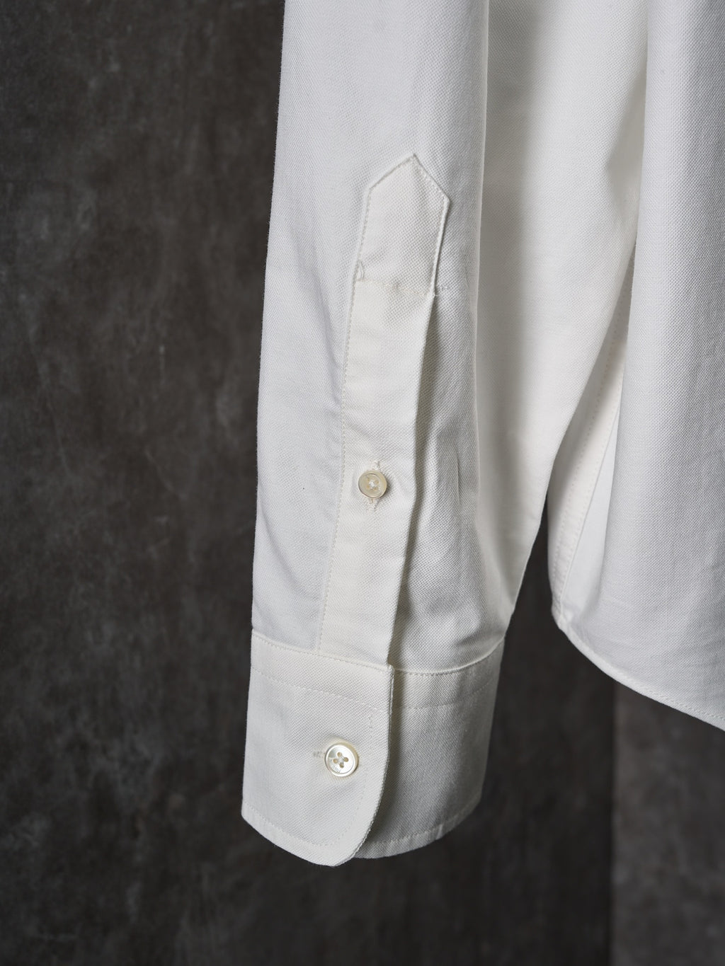 White buttoned shirt sleeve with stitched pocket panel and gold buttons