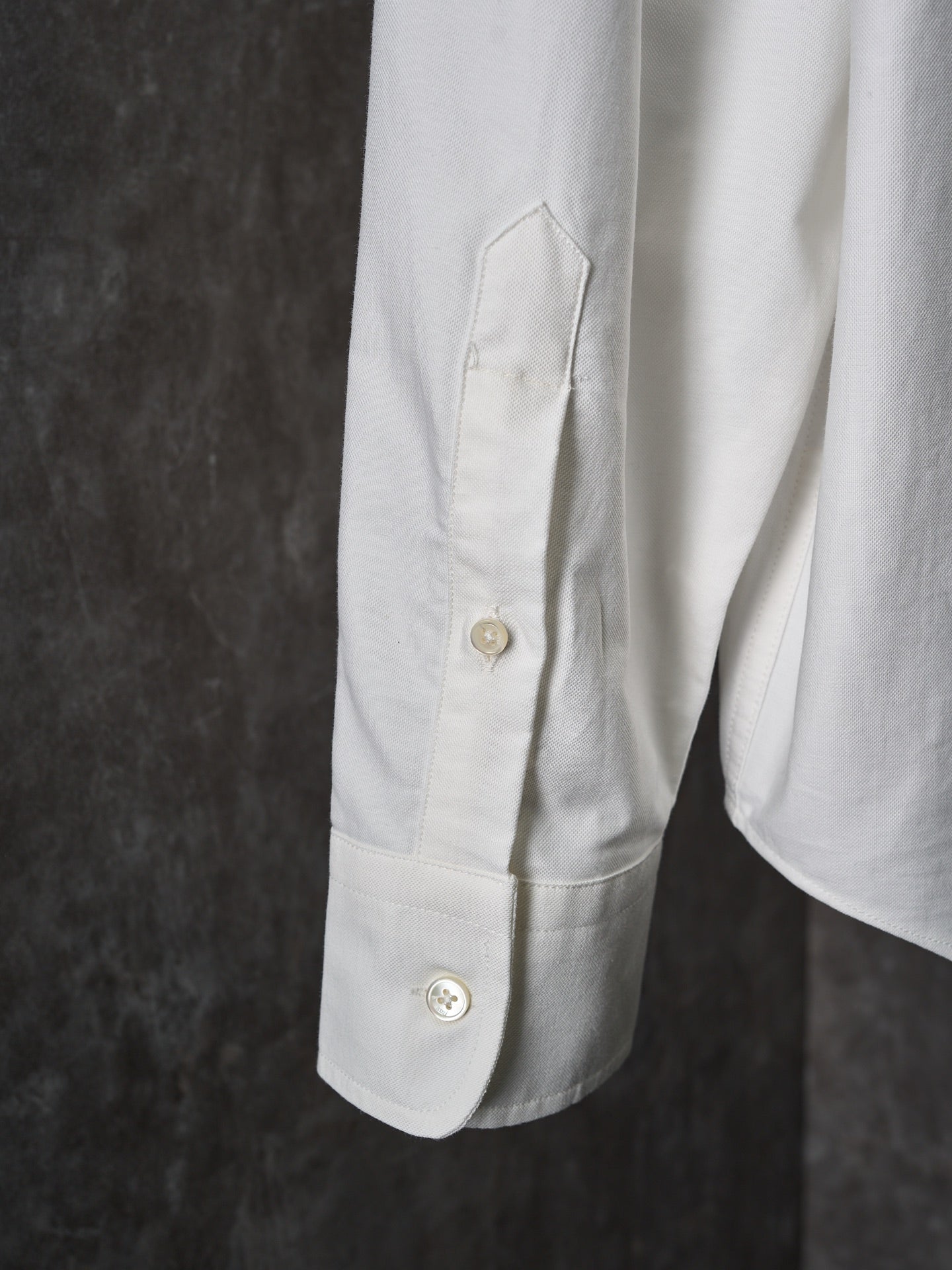 White buttoned shirt sleeve with stitched pocket panel and gold buttons
