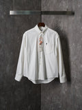 White button-up shirt with pointed collar, chest pocket, and gold buttons