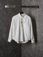 White button-up shirt with pointed collar, chest pocket, and gold buttons