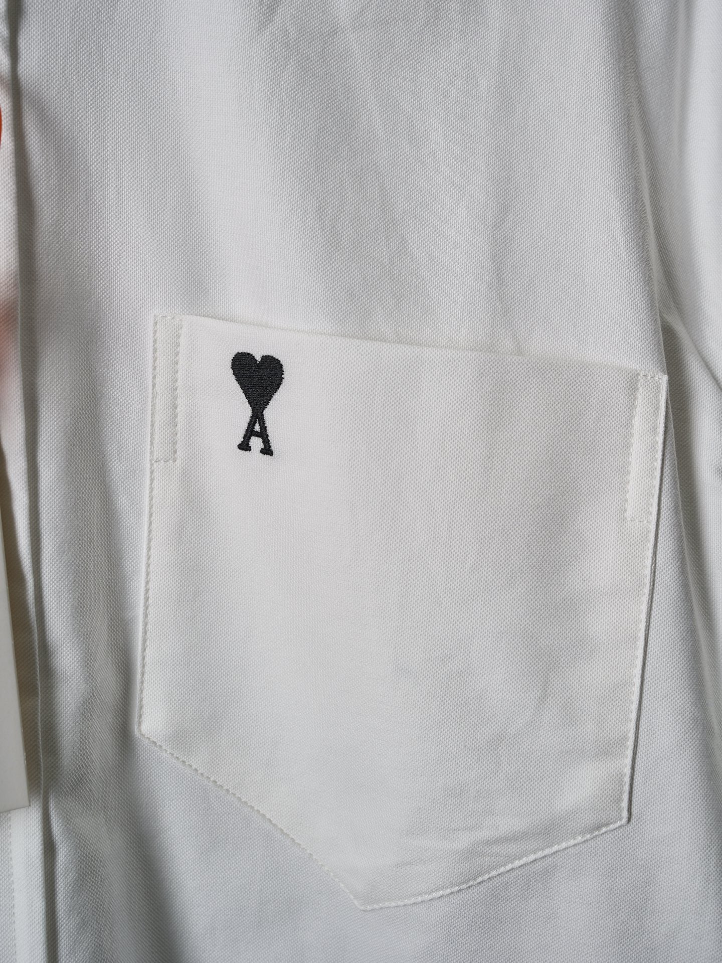 White chest pocket with black heart "A" emblem