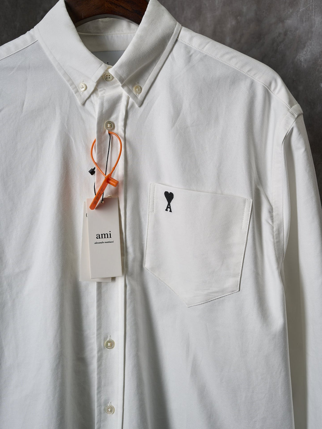 White button-up shirt with front pocket and black heart "A" logo