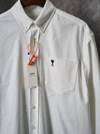 White button-up shirt with front pocket and black heart "A" logo