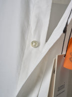 White shirt cuff with gold button and orange hanger tag