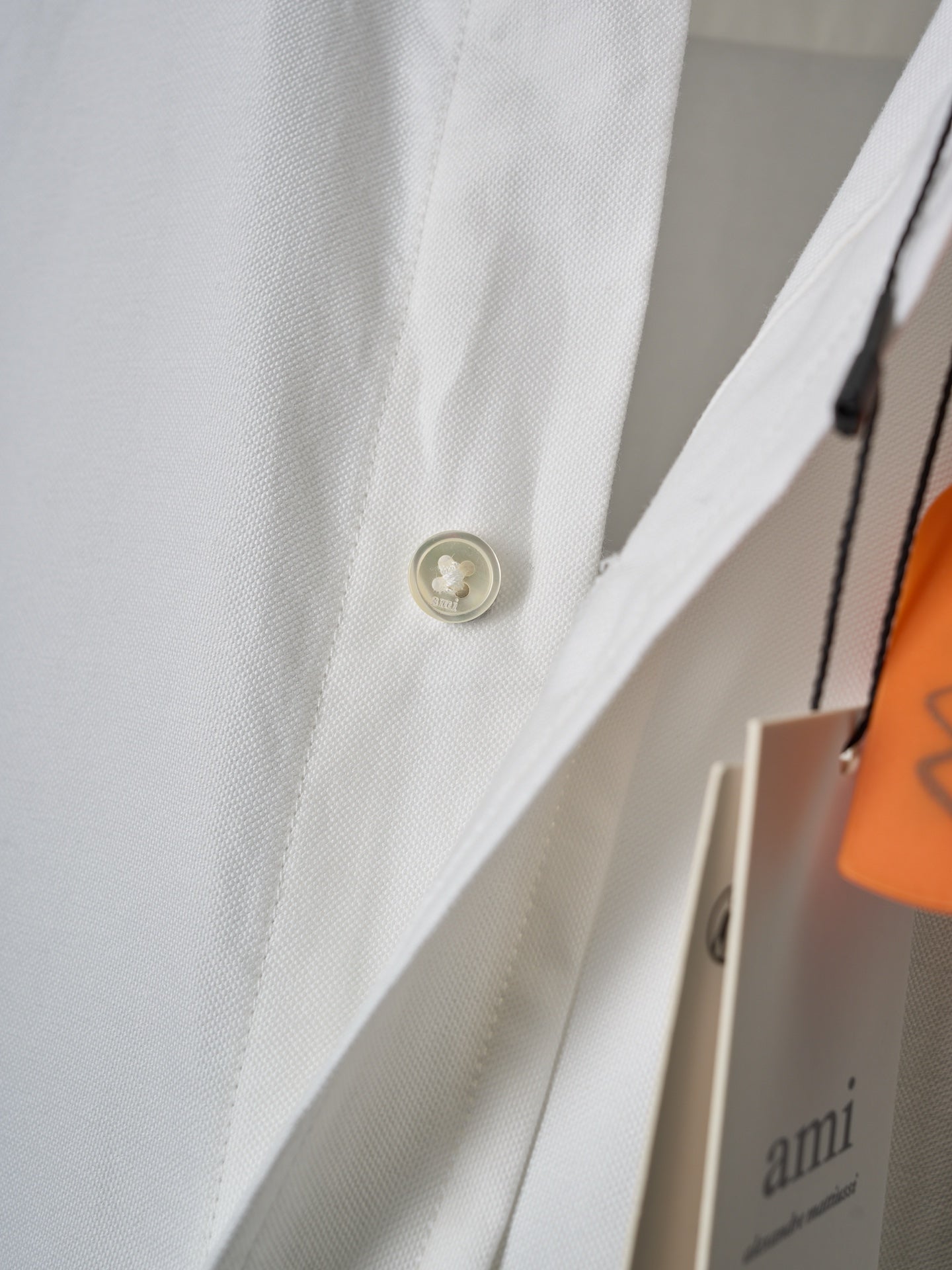 White shirt cuff with gold button and orange hanger tag