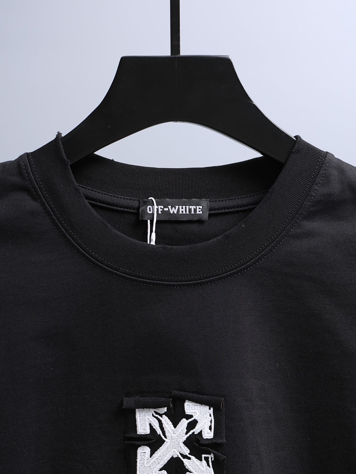 Off-White black T-shirt neckline with inner brand label and small chest patch graphic