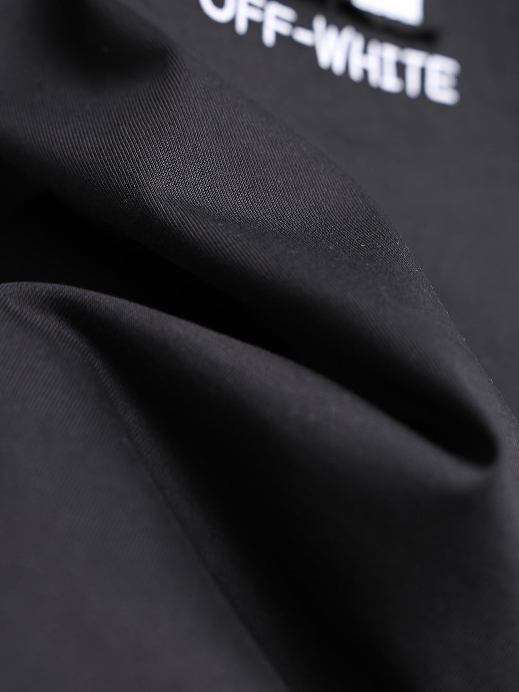 Off-White black T-shirt fabric close-up with partial logo text
