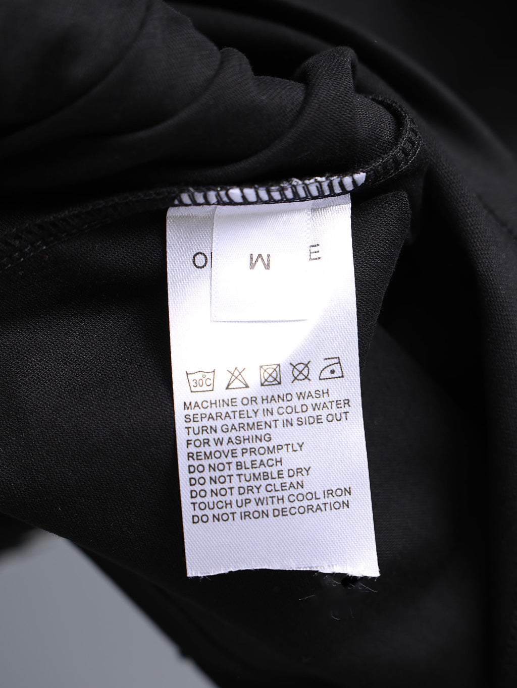 Garment care label on dark fabric collar area