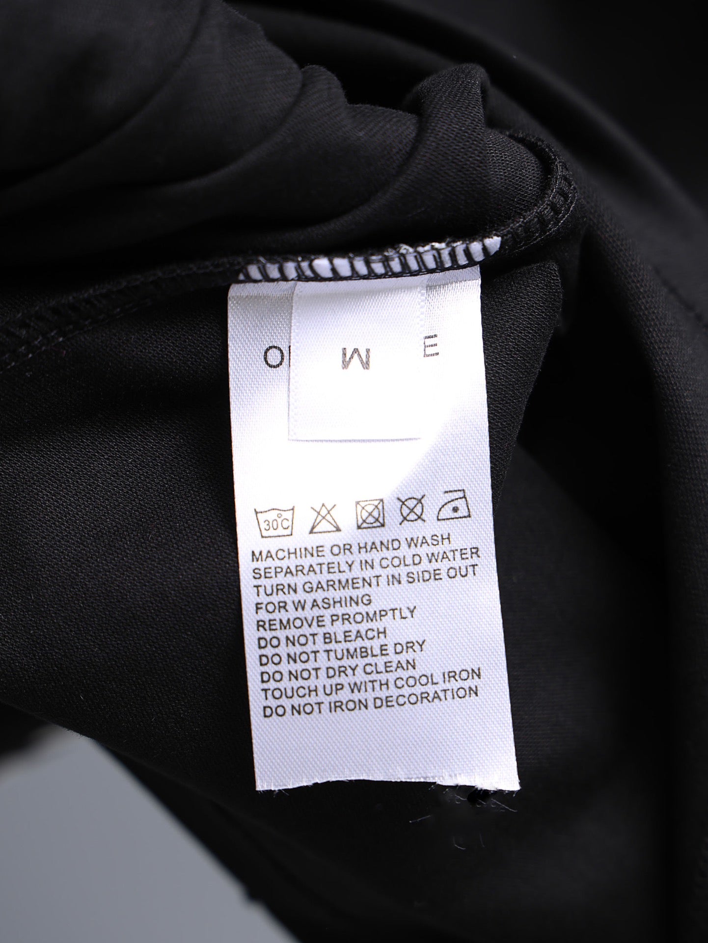 Garment care label on dark fabric collar area