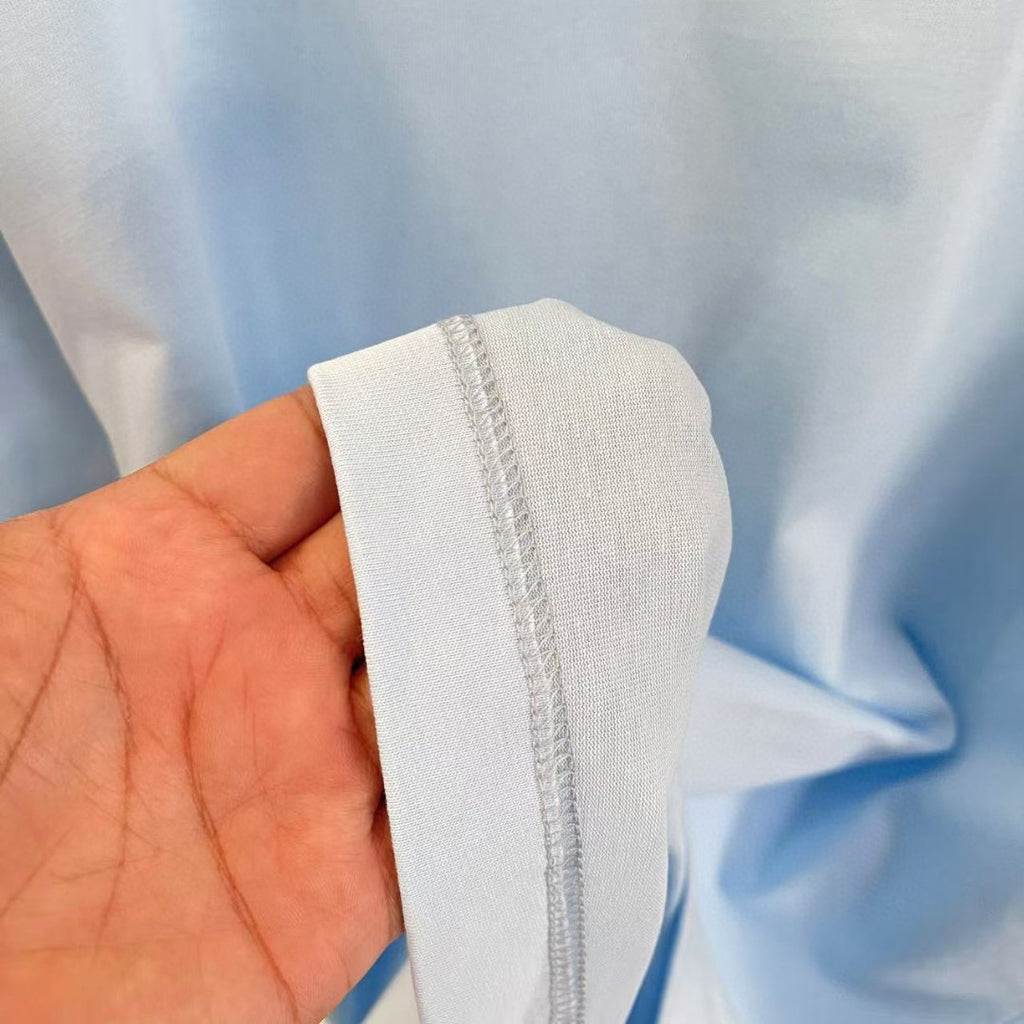 Light blue T-shirt sleeve cuff close-up with visible stitching and hem edge
