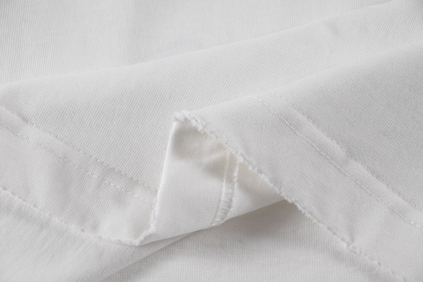 White short-sleeve T-shirt fabric with visible stitching at hem