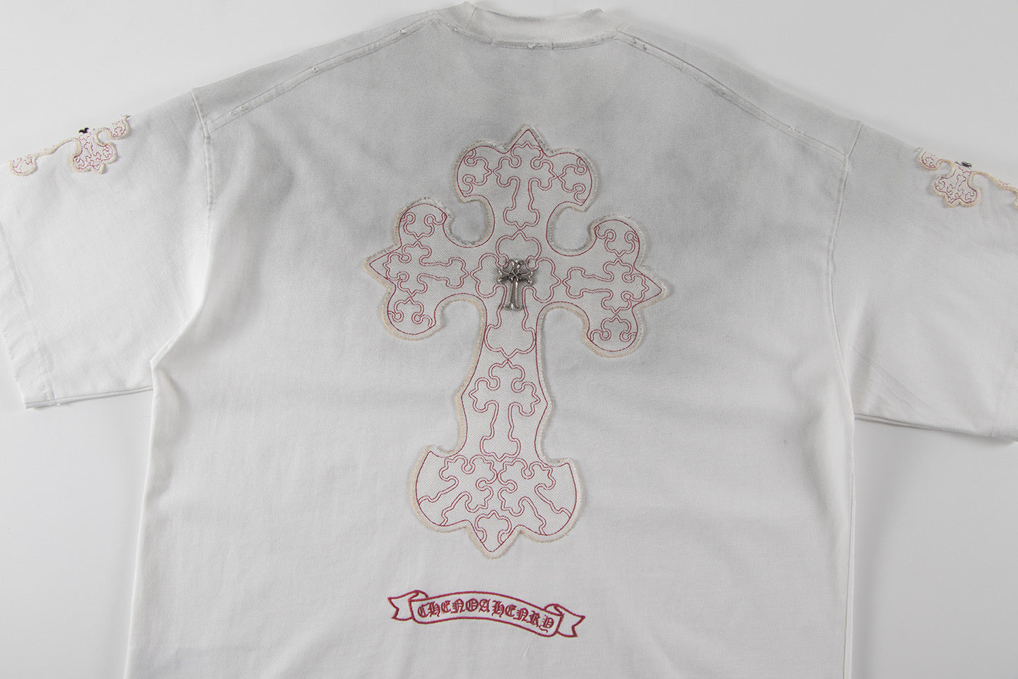 Back view of white short-sleeve T-shirt with large cross embroidery and logo patch