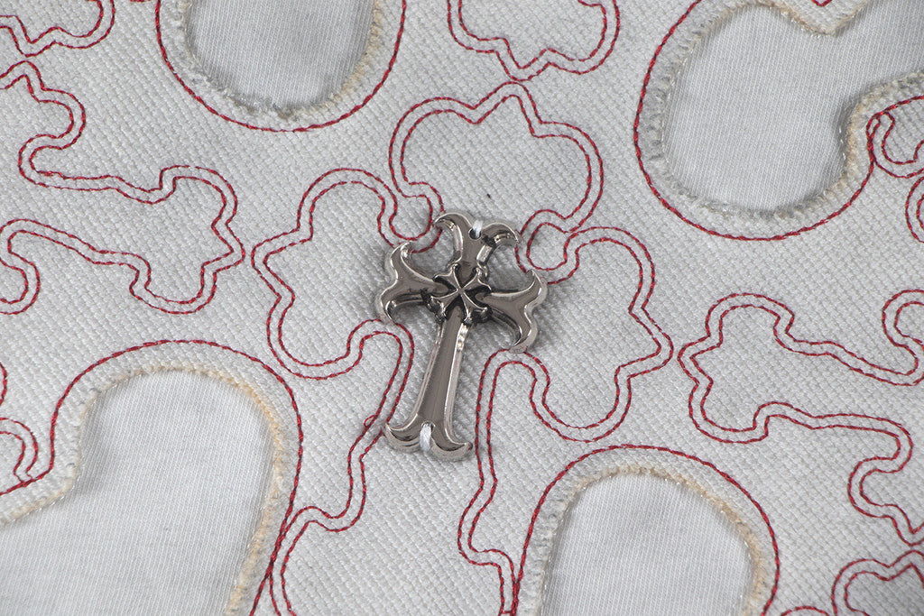 Close-up of embroidered cross patch with metallic centerpiece on T-shirt
