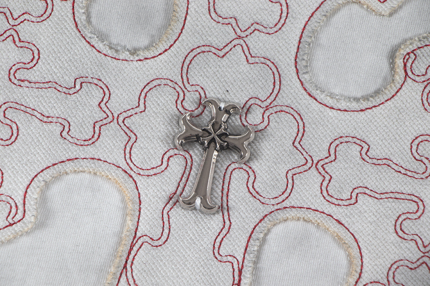 Close-up of embroidered cross patch with metallic centerpiece on T-shirt