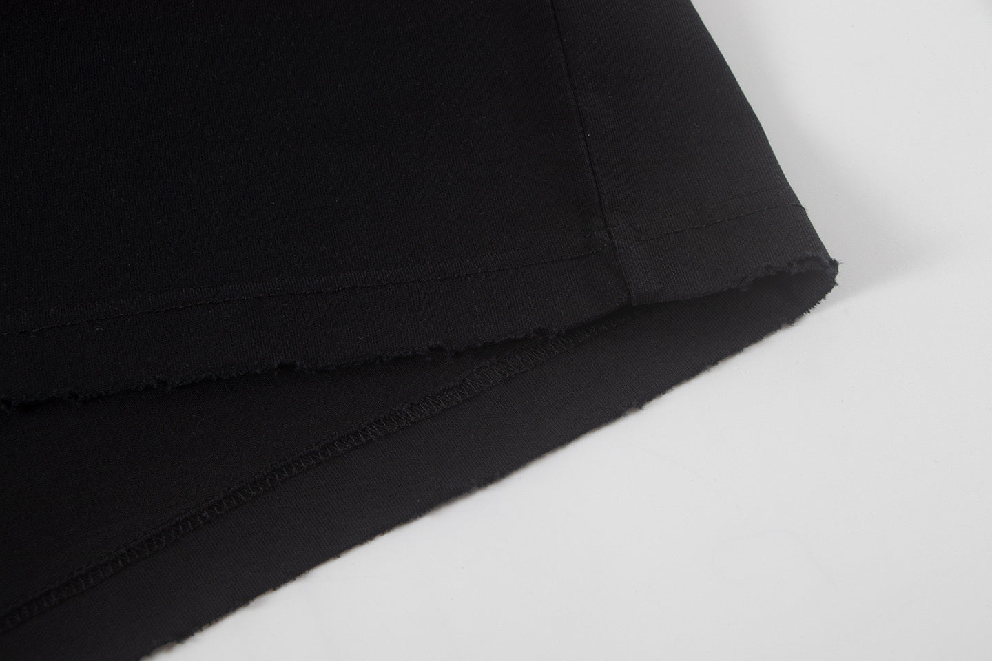 Black short-sleeve shirt hem with visible stitching and finish