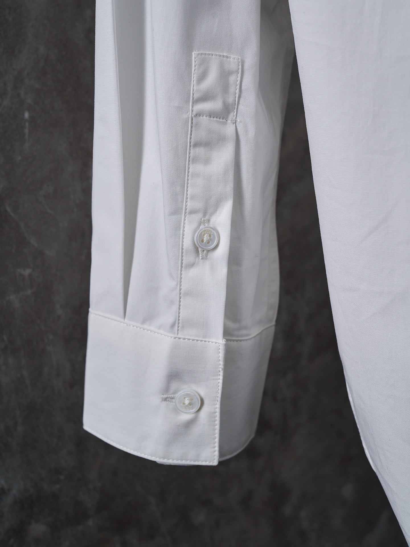 Dior white shirt sleeve cuff with buttoned placket and visible topstitching
