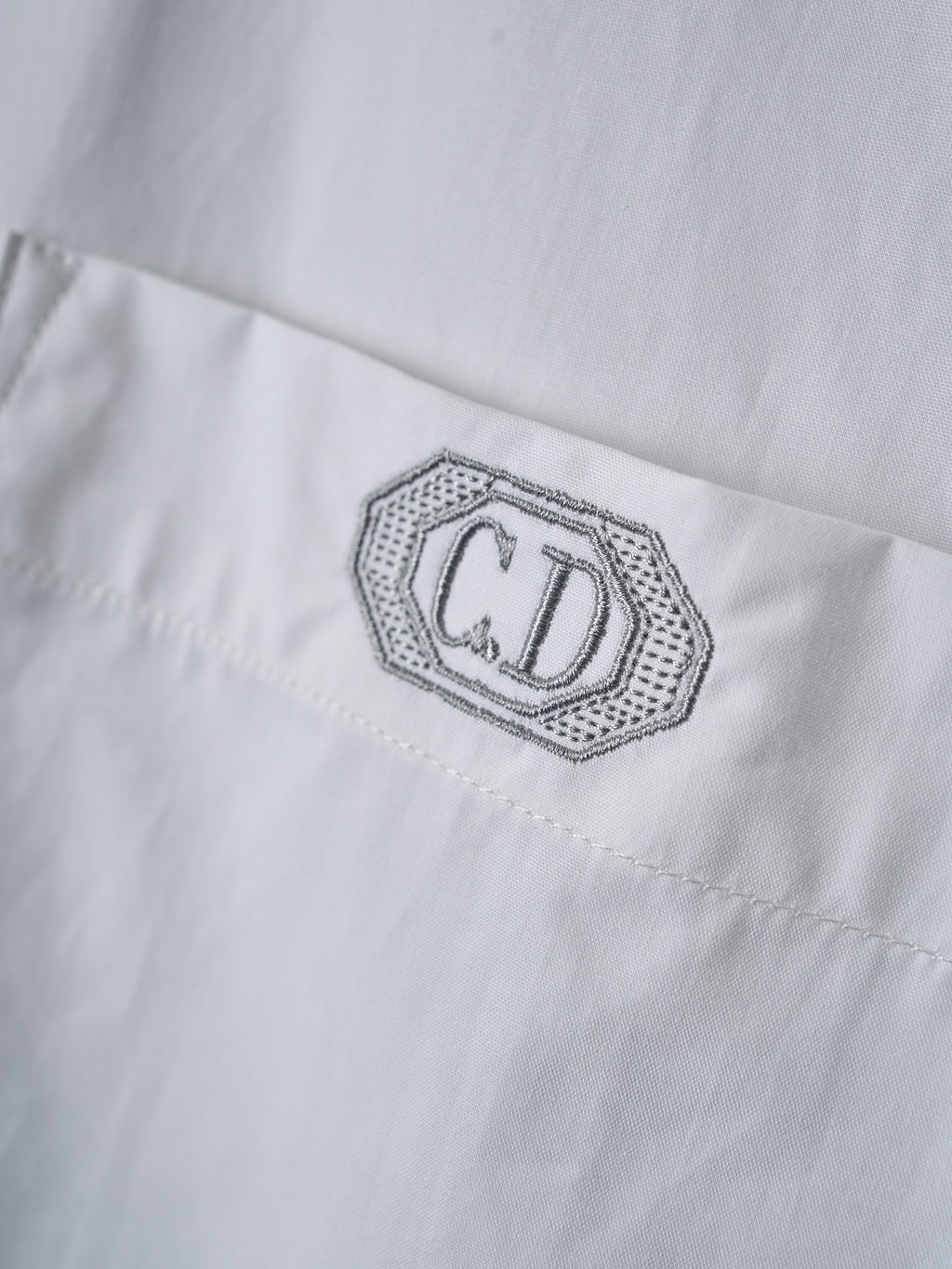 Dior embroidered logo patch on white fabric with fine dotted border stitching