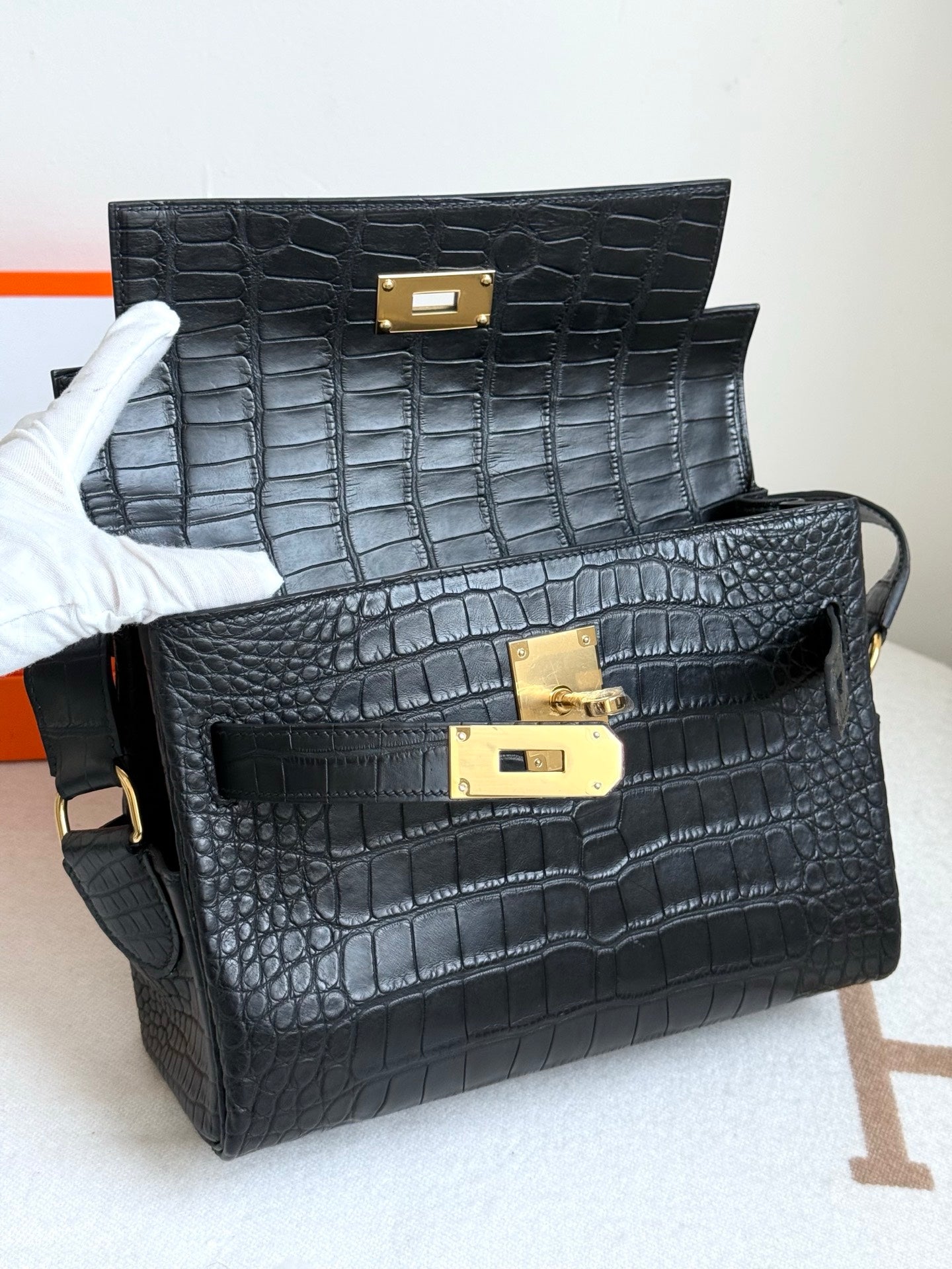 Hermes croc-textured handbags, dark blue with gold turn-lock closures, stacked view