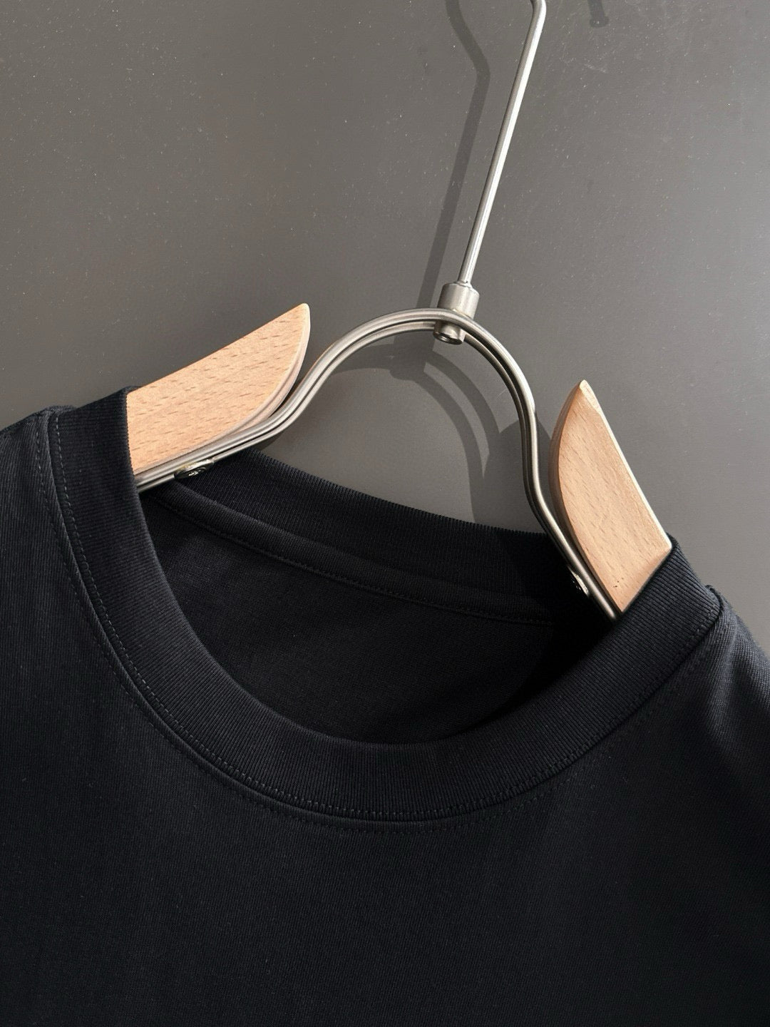 Black T-shirt neckline on a hanger with wooden clips