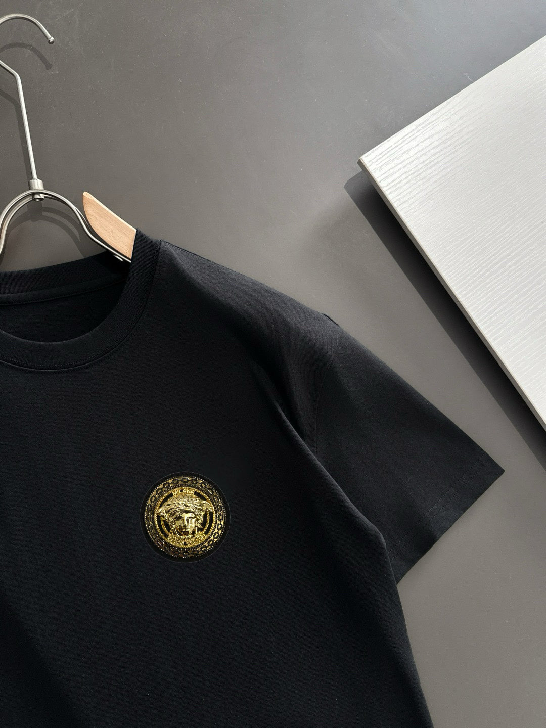 Black short-sleeve T-shirt with gold crest on chest