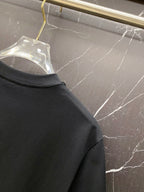 Black T-shirt shoulder and sleeve seam detail, crew neckline edge visible