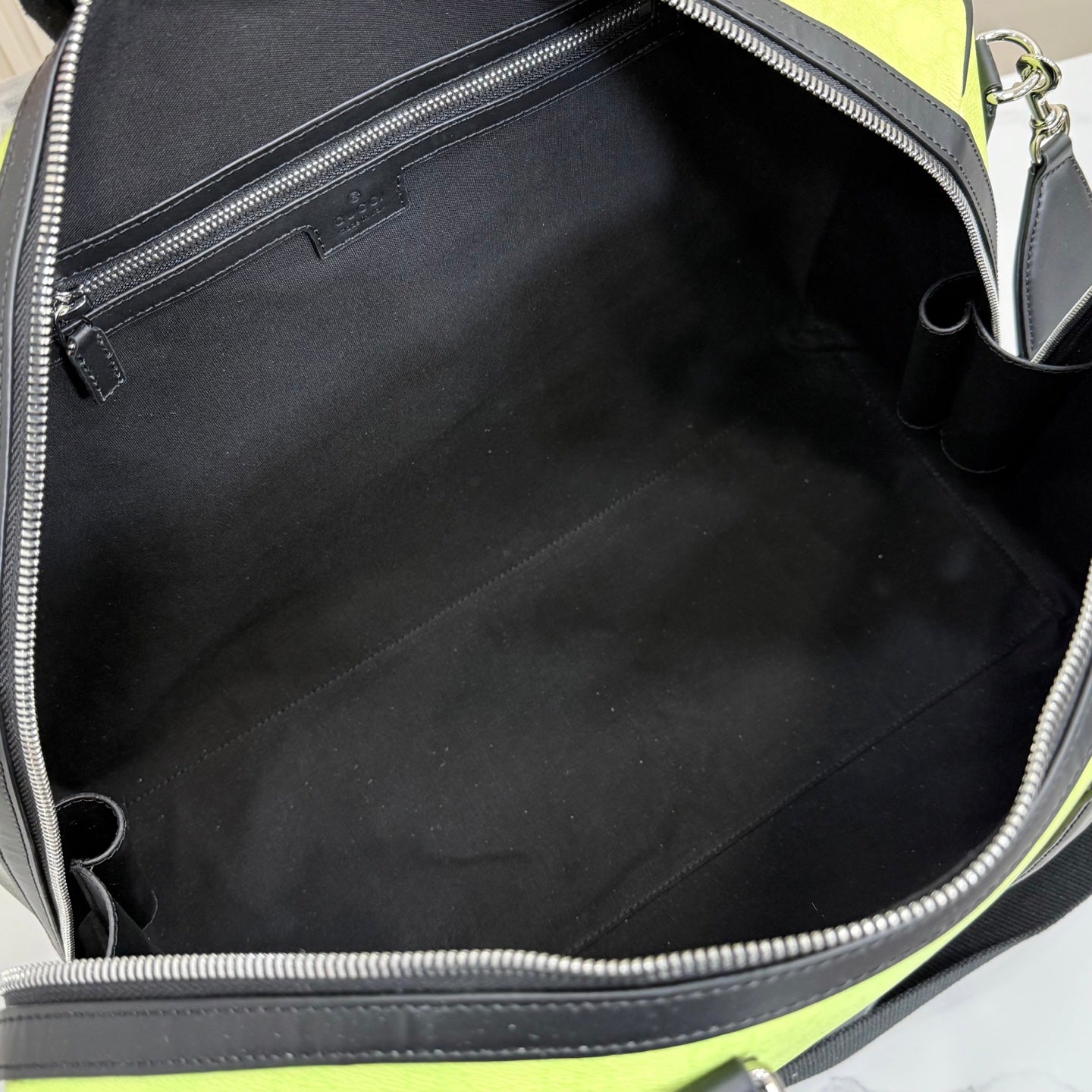 Duﬀel bag interior with black lining and silver zipper at the open top