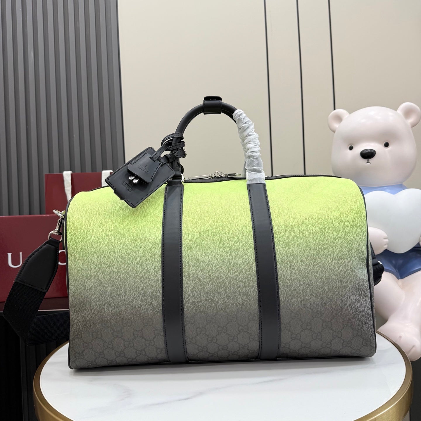 Gucci duffel bag with lime-green top and dark gray monogram body, black handles