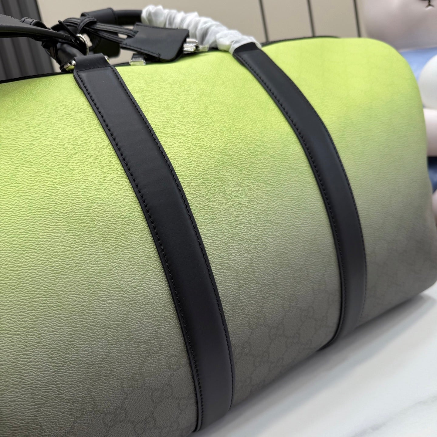 Green duffel bag close-up: black-trimmed stripe, monogram fabric, textured leather