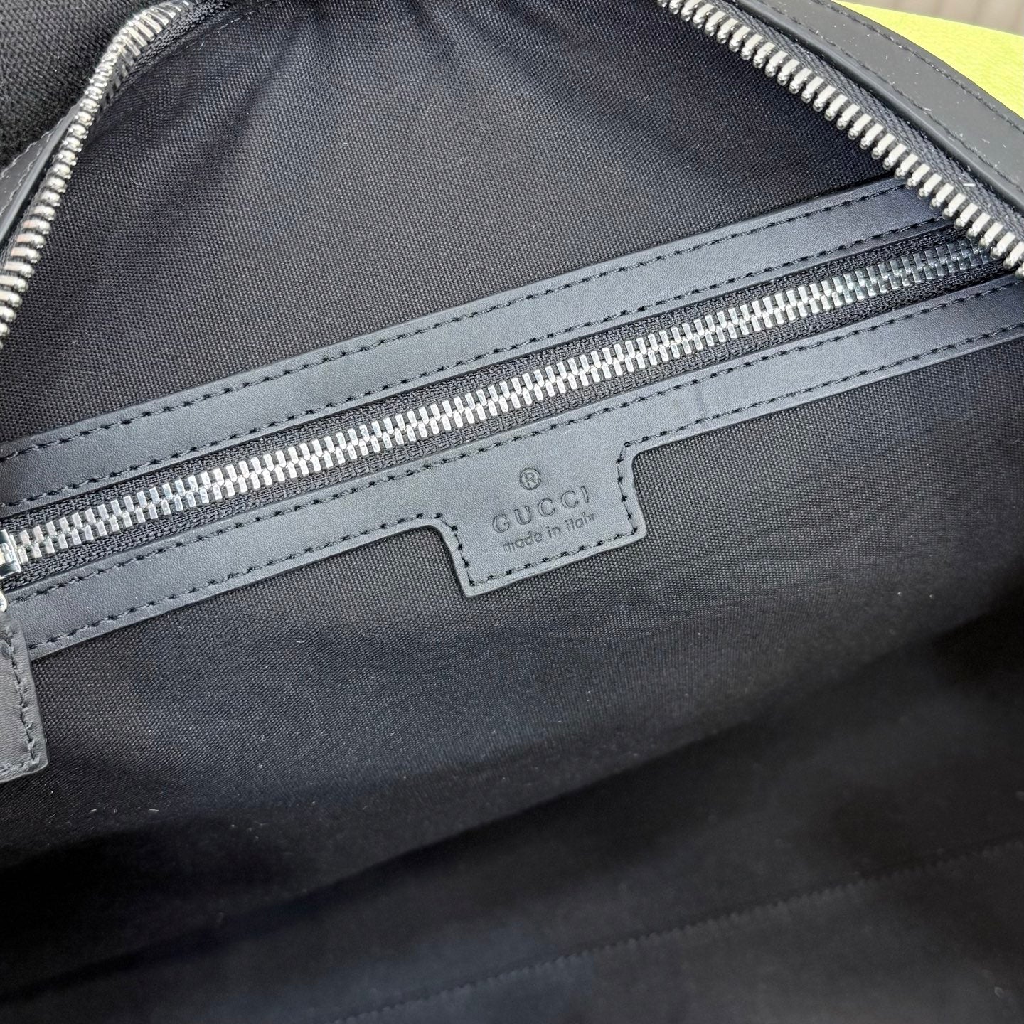 Monogram duffel bag close-up: Gucci label, silver zip track, black leather trim