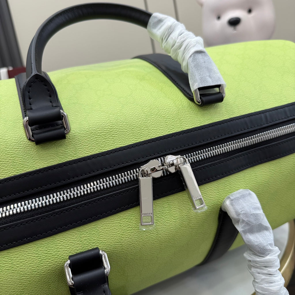 Green duffel bag close-up of top handle and silver zipper pull with black trim