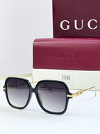 Black square sunglasses with dark lenses and gold-tone temple detail