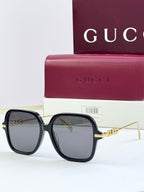 Black square sunglasses with dark lenses and gold-tone temple detailing