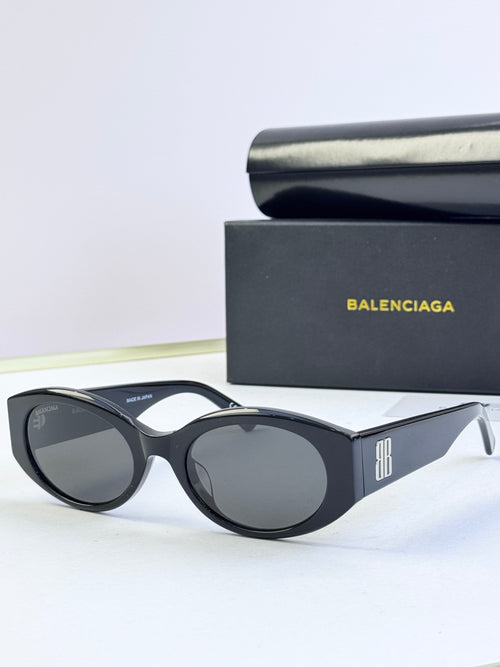 Sunglasses with black oval frames, dark lenses, and logo detail at the temple