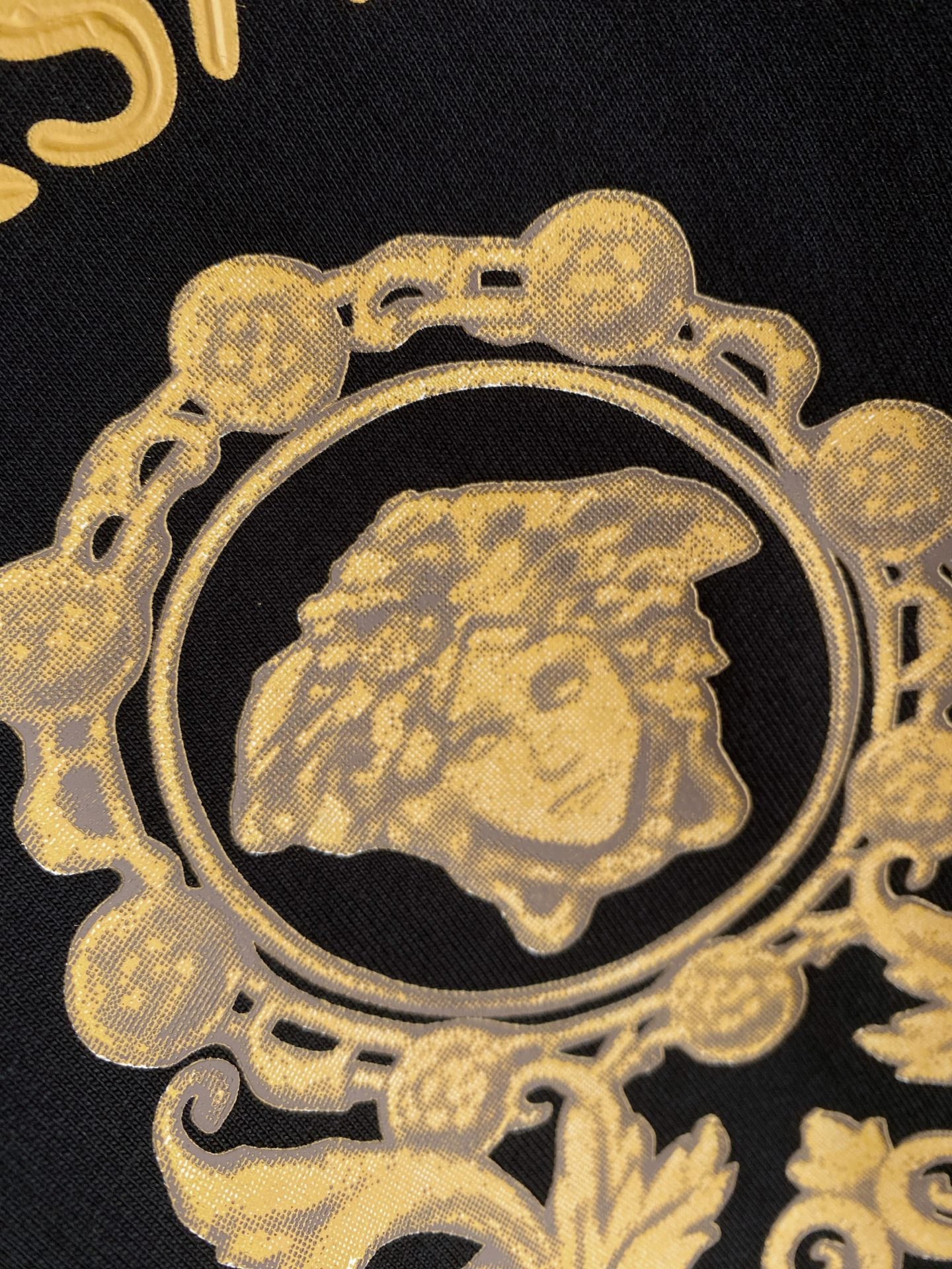 Versace T-shirt medallion close-up with gold crown emblem and VERSACE