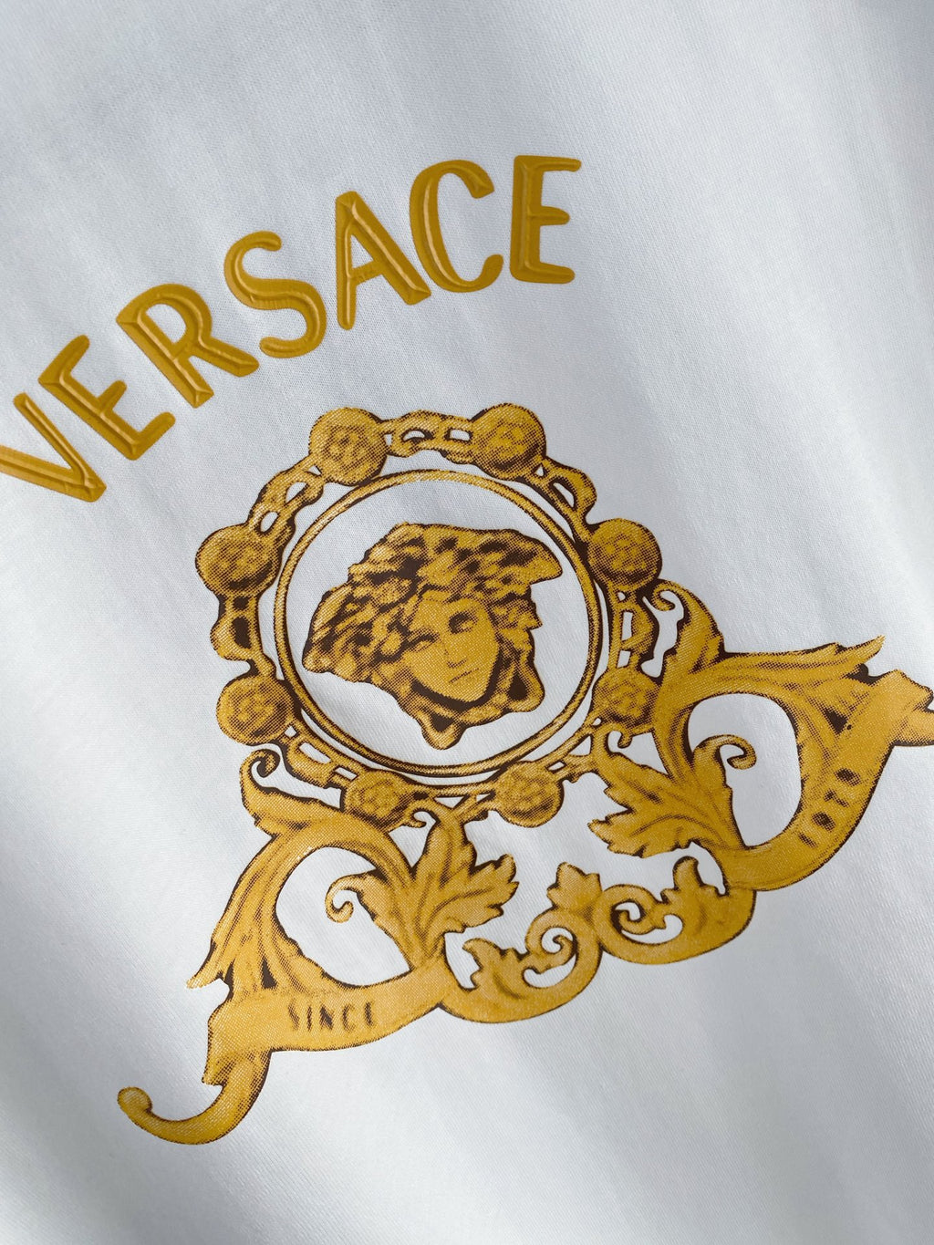 White T-shirt featuring a gold Versace crest and portrait print