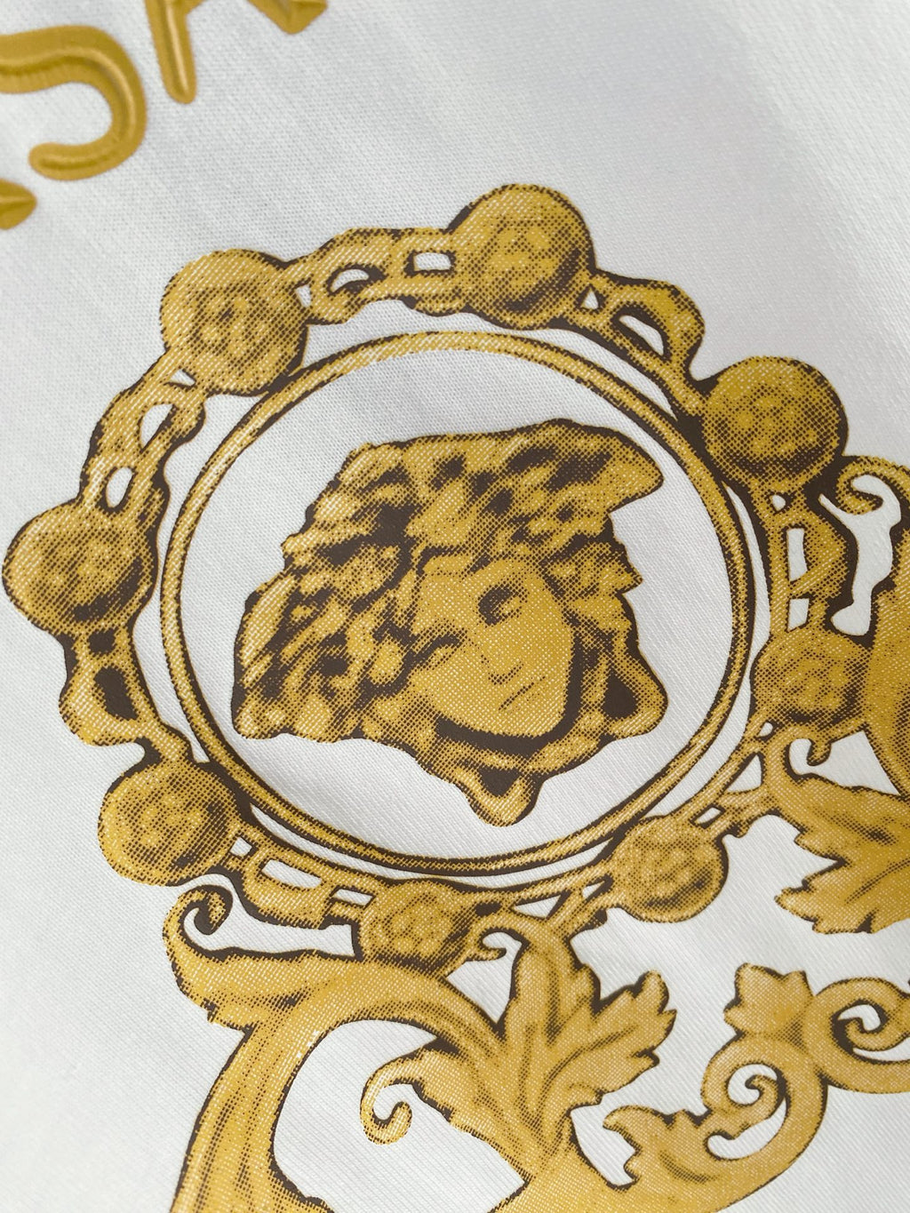 White T-shirt close-up of gold Versace crest portrait graphic