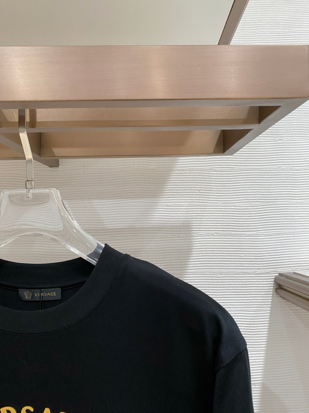 Versace T-shirt shoulder close-up with gold VERSACE lettering on chest