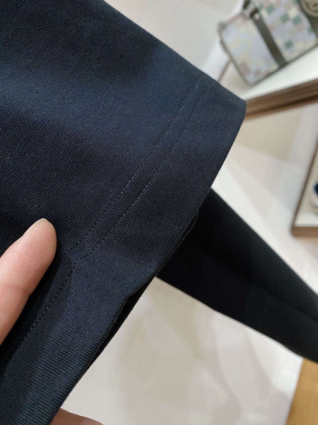 Versace T-shirt sleeve and hem close-up on dark knit fabric
