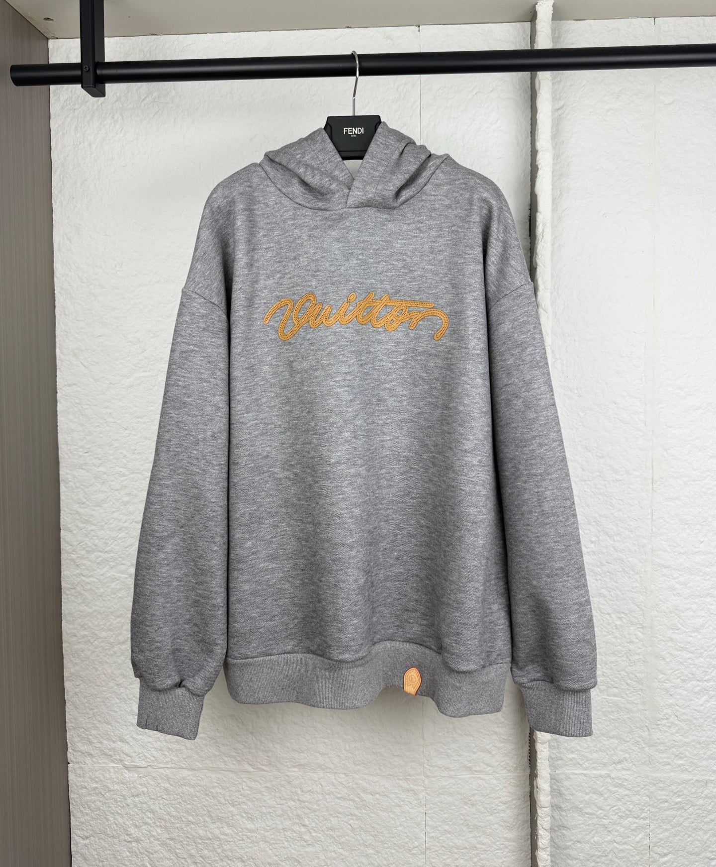 Gray marl hoodie with yellow embroidered script logo, pullover hood, and front pouch pocket