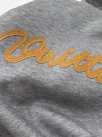 Gray hoodie with yellow embroidered script logo across the chest