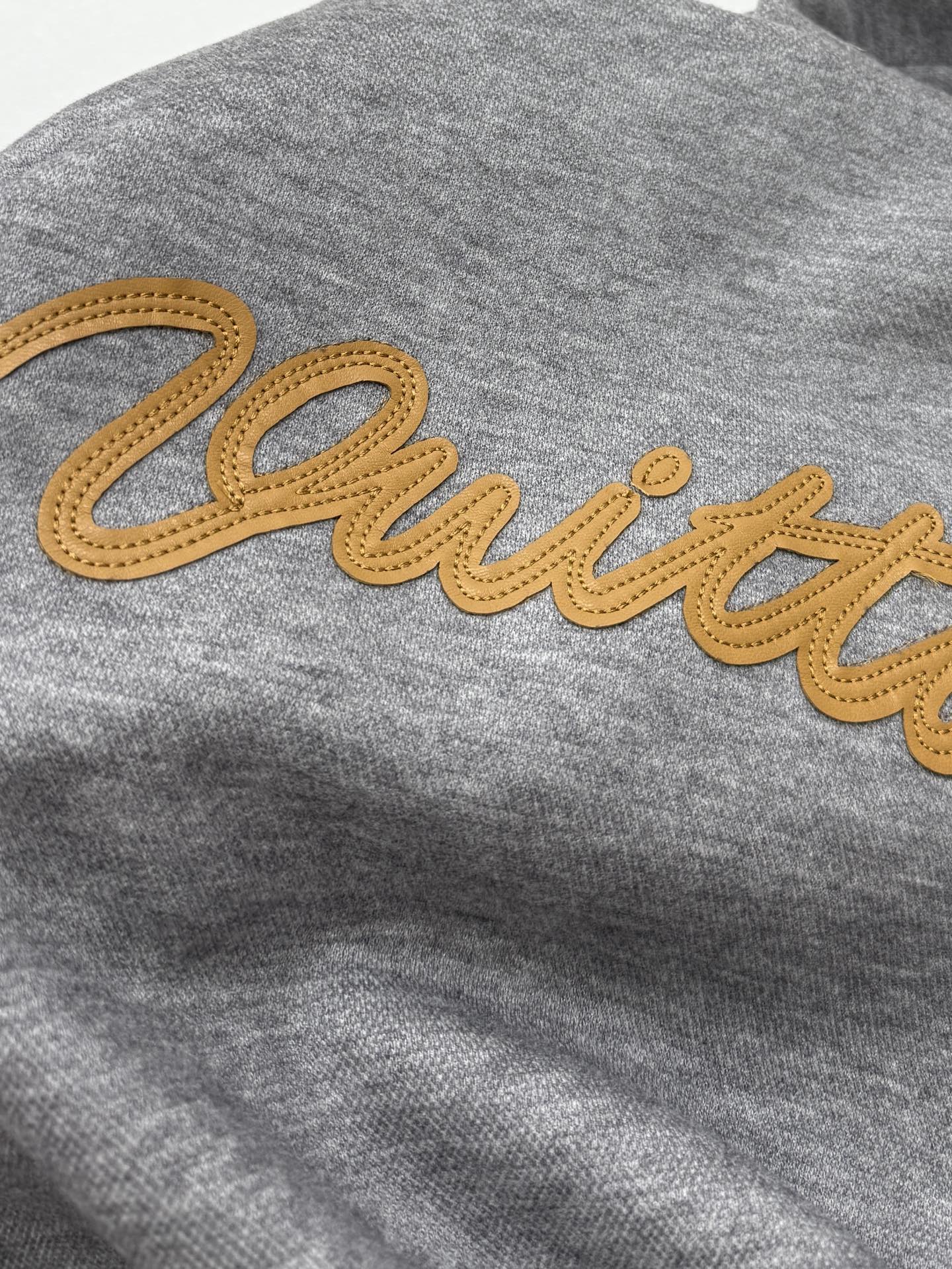 Gray hoodie with yellow embroidered script logo across the chest