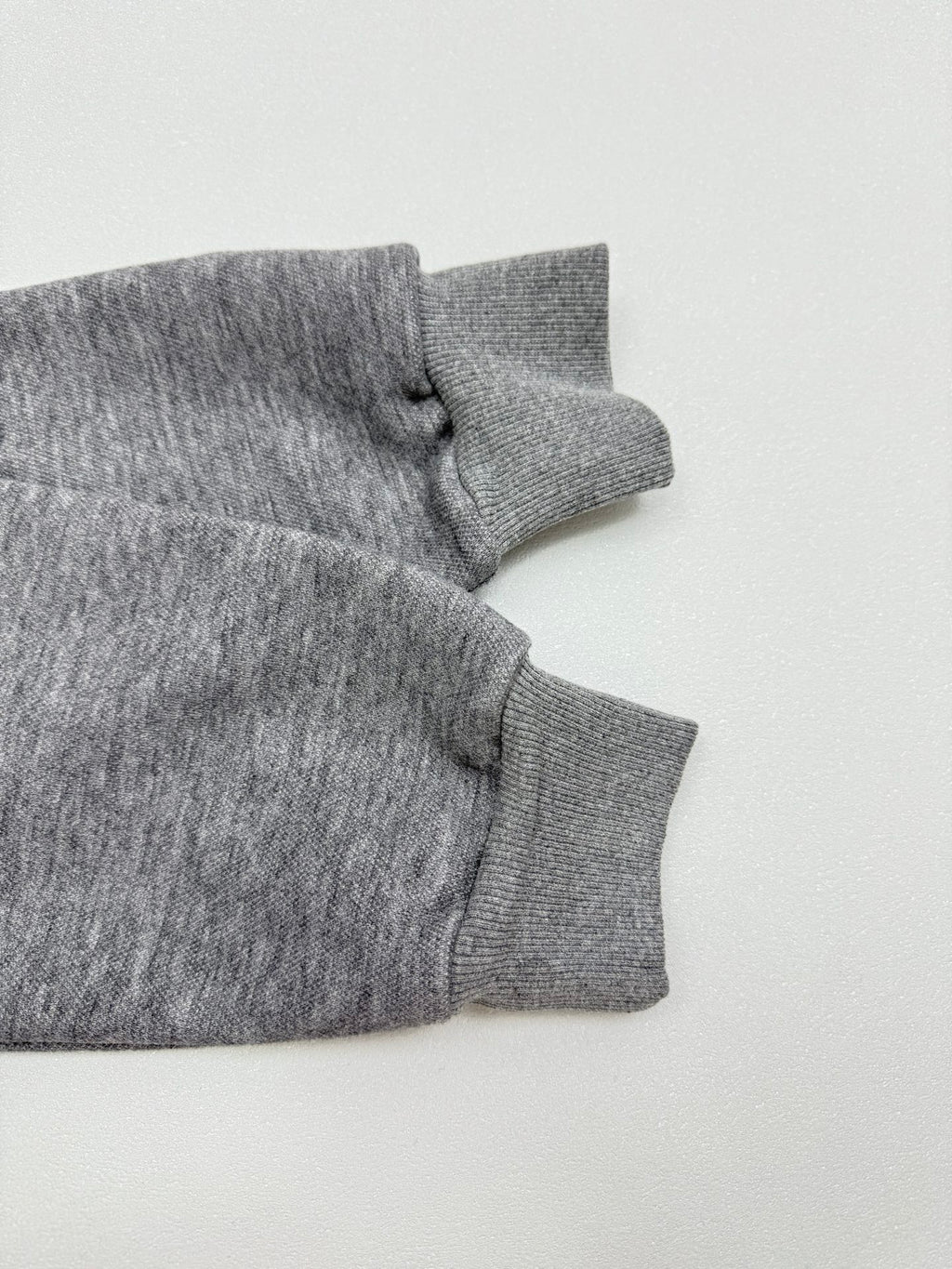 Gray hoodie sleeve with ribbed cuff and gathered seam near the shoulder