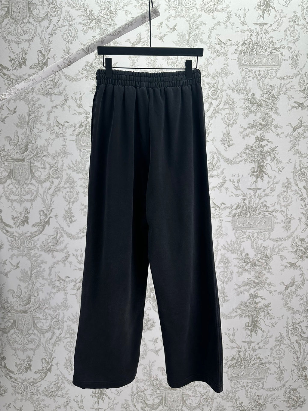 Balenciaga dark wide-leg pants, front view, elastic waistband and logo patch