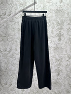 Balenciaga dark wide-leg pants, front view, elastic waistband and logo patch